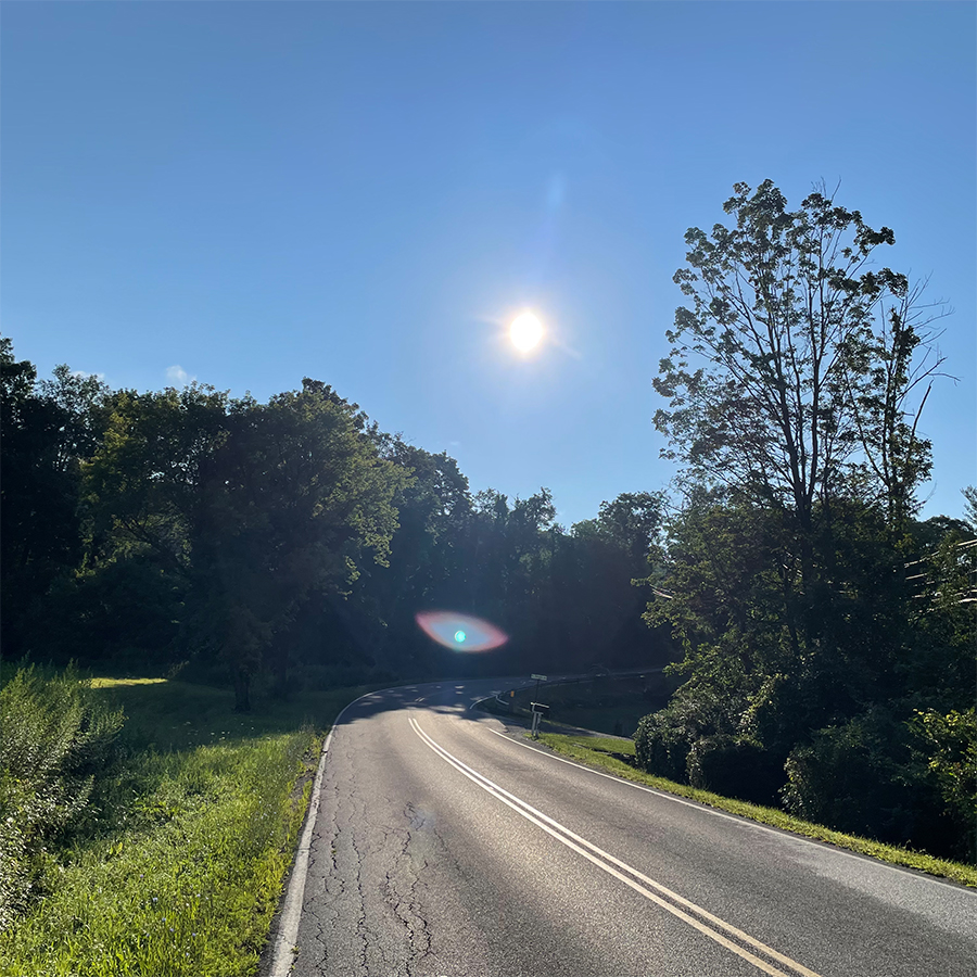 photo of curving road with sunbeam portal