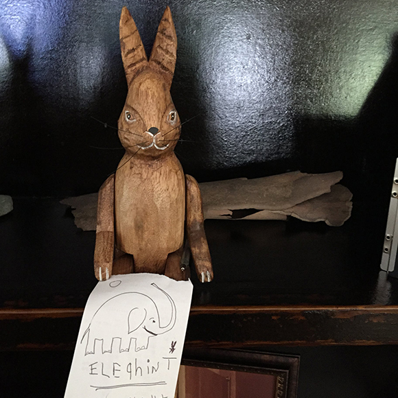 carved wood rabbit holding primitive sketch of elephant spelled elighint